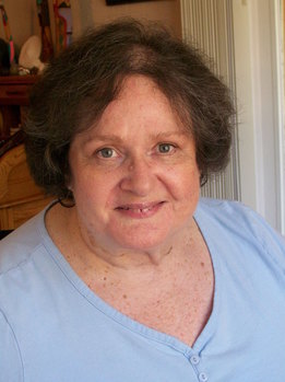 A headshot of Lillian Gonzales Brown, who is smiling, has short brown hair and brown eyes, and is wearing a light blue shirt. 